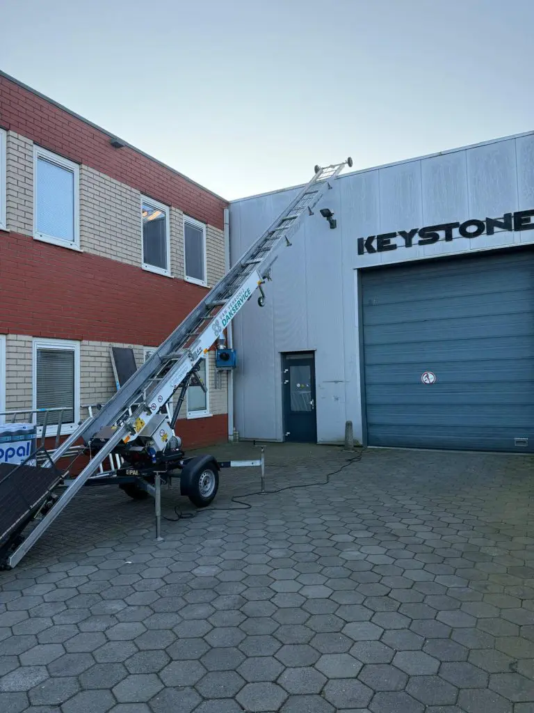 Steiger met Van Venrooij Dakservice logo geplaatst tegen een bedrijfspand voor dakwerkzaamheden.