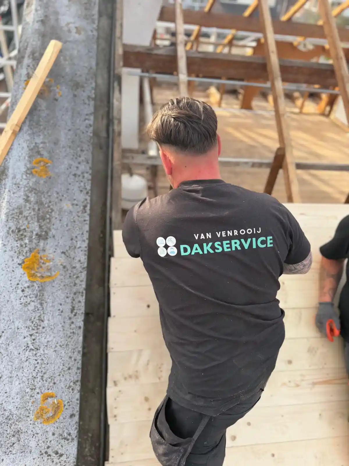 Dakdekker met Van Venrooij Dakservice shirt werkt aan houten dakconstructie bij renovatie of nieuwbouw.